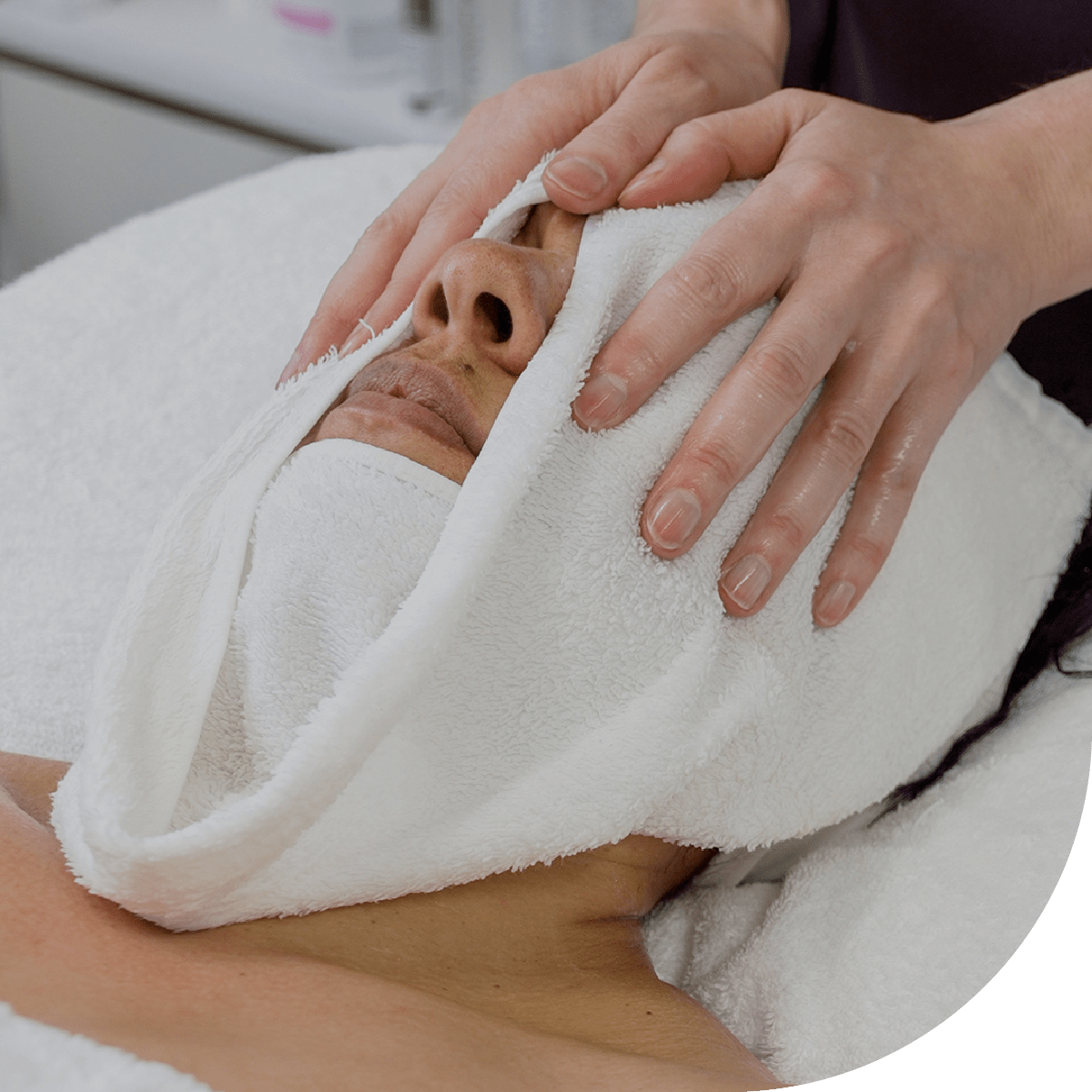 Person receiving a facial with a towel on their face in a spa setting