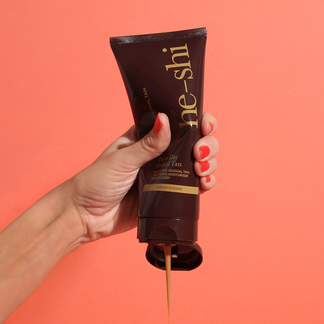 Image of a hand squeezing He-Shi Dark Day to Day Gradual bottle being squeezed to show the creamy texture of the product 