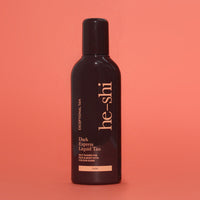 Bottle of he-shi Dark Express Liquid Tan on a coral background