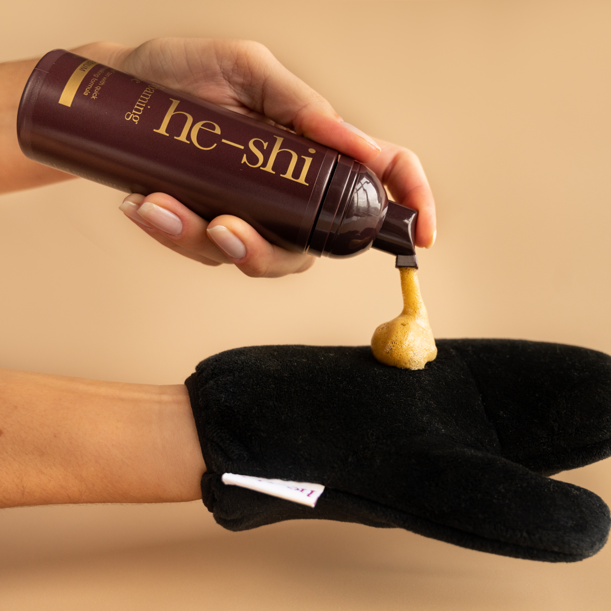 Image of hand pumping He-Shi Gold Foaming Mousse onto a tanning mitt
