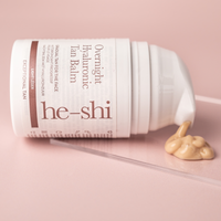 He-shi Overnight Hyaluronic Tan Balm laying on its side with the product pouring out to show the creamy texture of the product