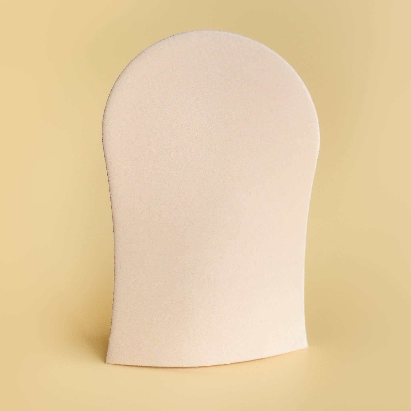 Image of He-Shi tanning mitt on a light yellow background