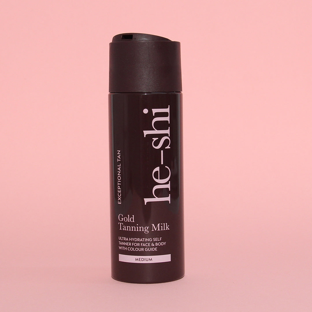 He-Shi Gold Tanning Milk bottle on pink background