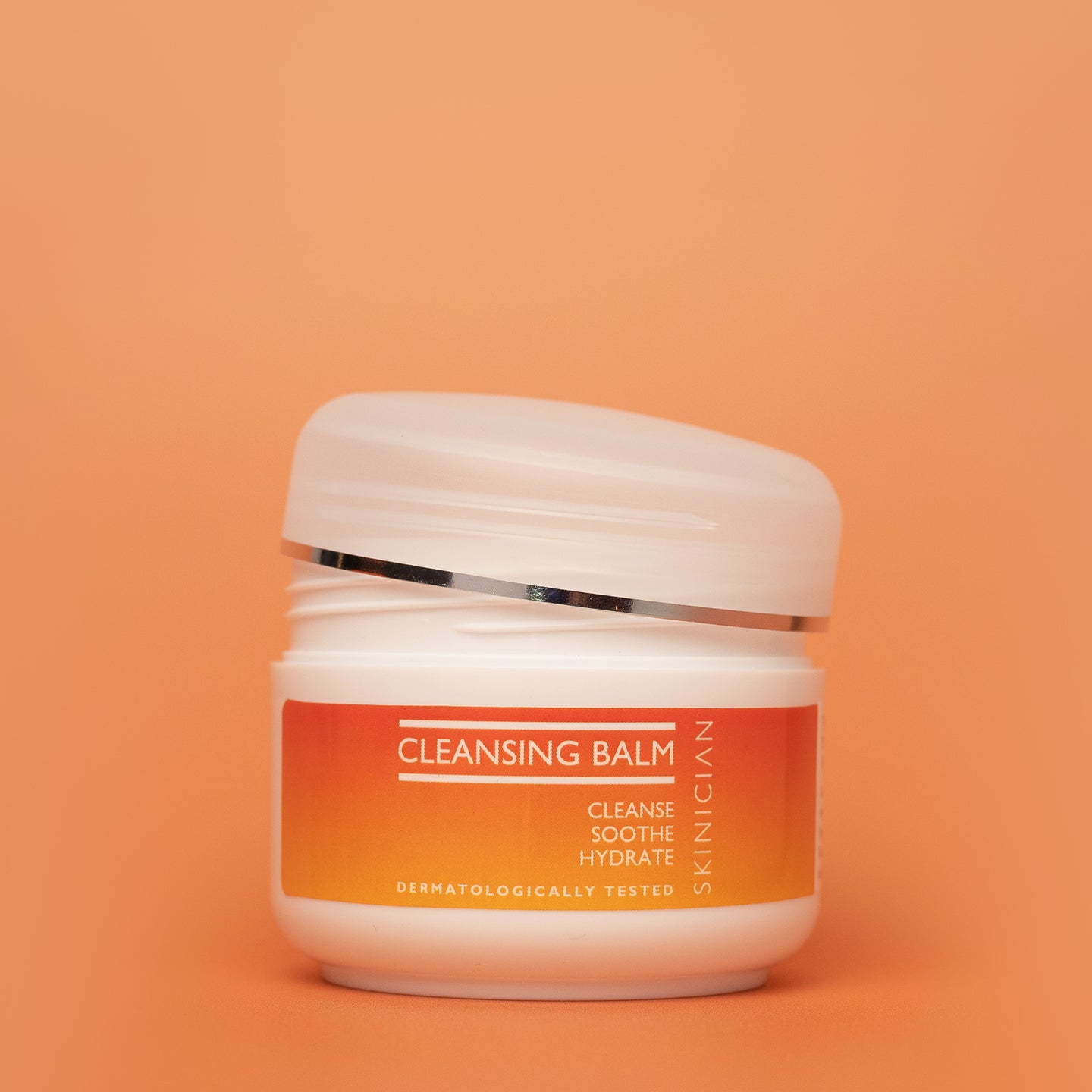 Cleansing balm jar with orange label on an orange background