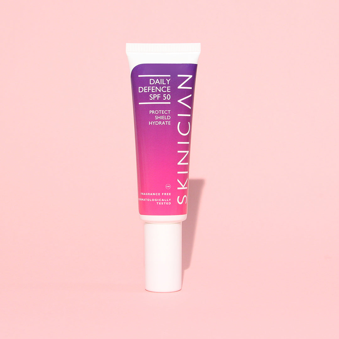 Tube of Skincian daily defense SPF 50 cream on a pink background