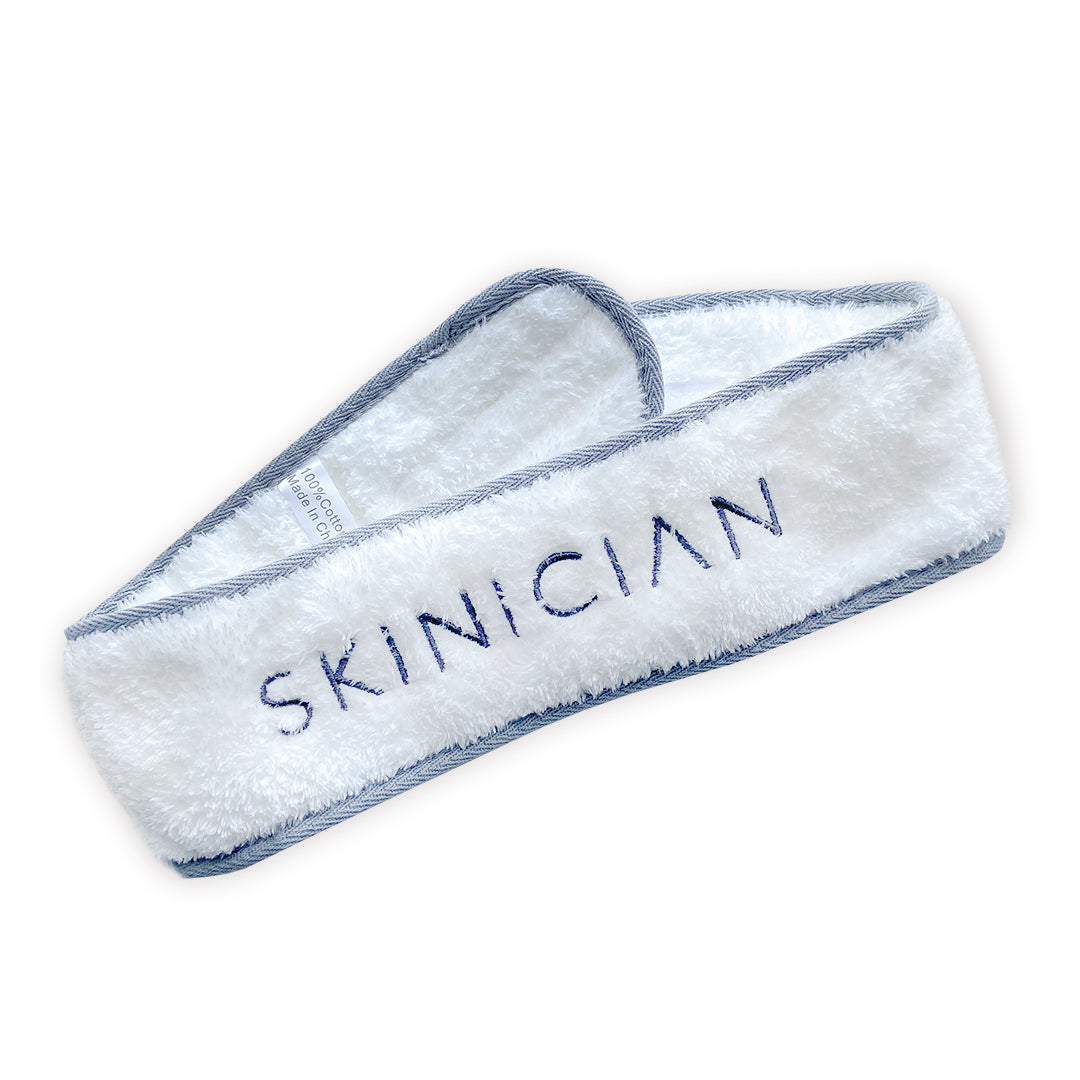 Image of Skinician facial headband. It is a soft white material with grey trim featuring the Skinician logo