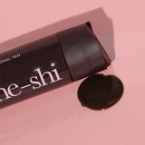 He-Shi Gold Tanning Milk bottle laying on its side with the product pouring out
