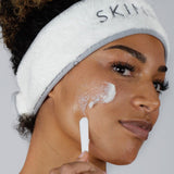 Woman applying Cleansing Balm to her check using a spatula to demonstrate the balm texture of the product