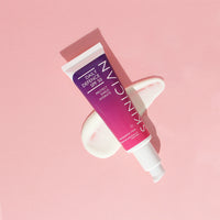 Tube of Skinician Daily Defense SPF 50 on a pink background with the product smeared underneath it